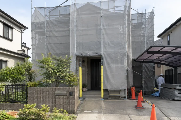 足場と養生を設けた戸建て。確保された玄関への通行経路が分かる。